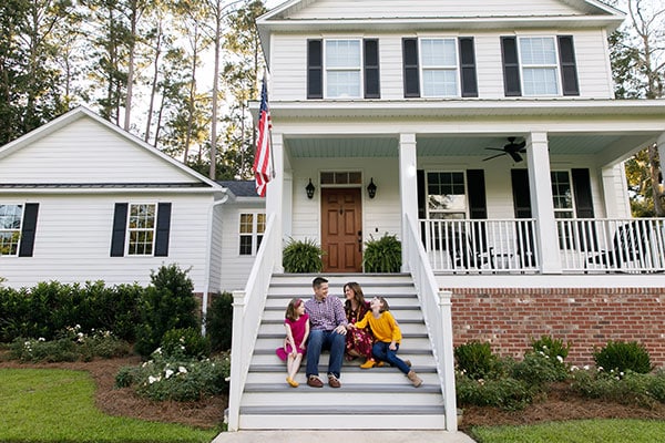 family sitting on porch in front of home with foundation repair completed