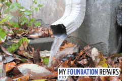 Downspout with water coming out of it, pooling around a foundation. 